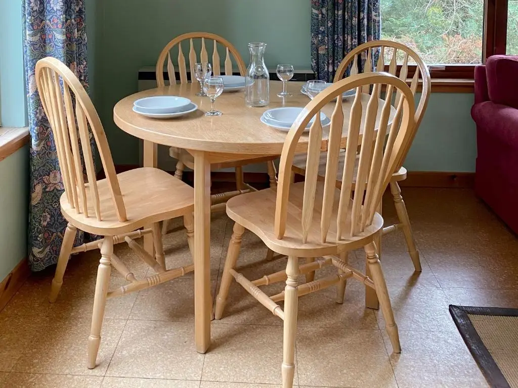a wooden table with four chairs and wine glasses at Kintulloch in Insh