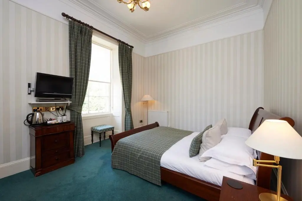 a hotel room with a bed and a television at Loch Ness Country House Hotel in Inverness