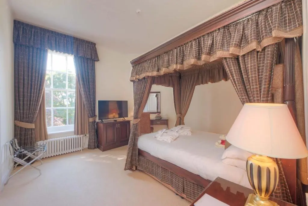 a bedroom with a canopy bed and a lamp at Muthu Newton Hotel (Near Inverness Airport) in Nairn