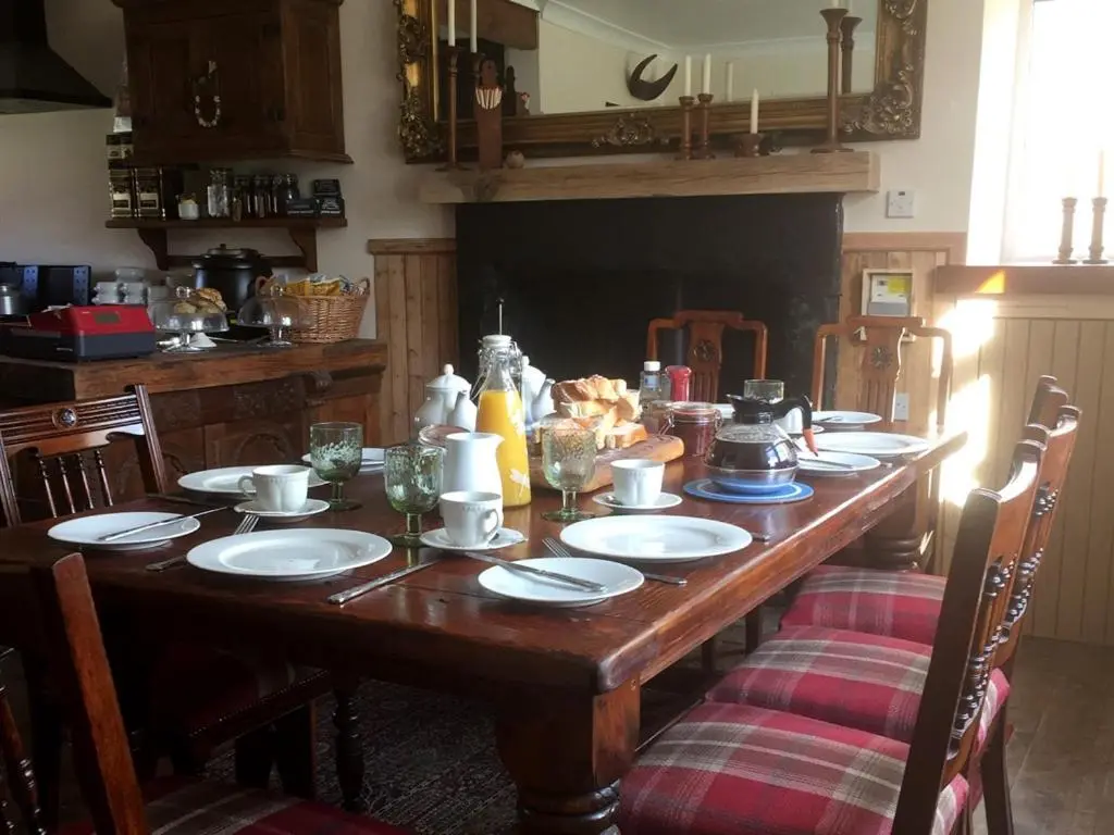 a wooden table with plates and dishes on it at Balsporran Bed And Breakfast in Dalwhinnie