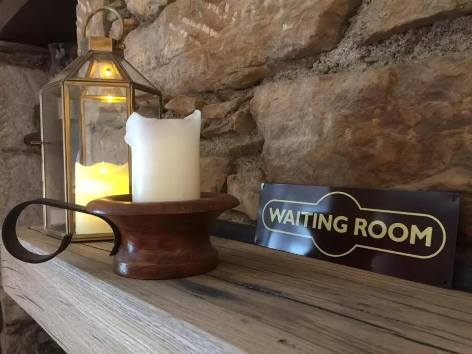 a candle on a table with a waiting room sign at Balsporran Bed And Breakfast in Dalwhinnie