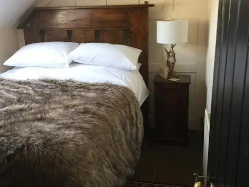 a bedroom with a bed and a lamp on a night stand at Balsporran Bed And Breakfast in Dalwhinnie