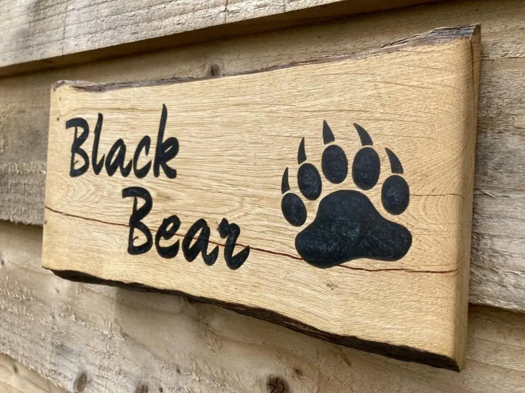 a black bear sign on a wooden wall at Highland Bear Lodge & Luxury Bear Huts in Drumnadrochit