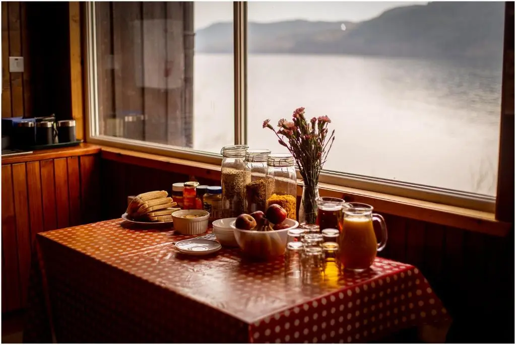 a table with a plate of food and a window at Loch Ness Lochside Hostel - Over 16s Only in Invermoriston