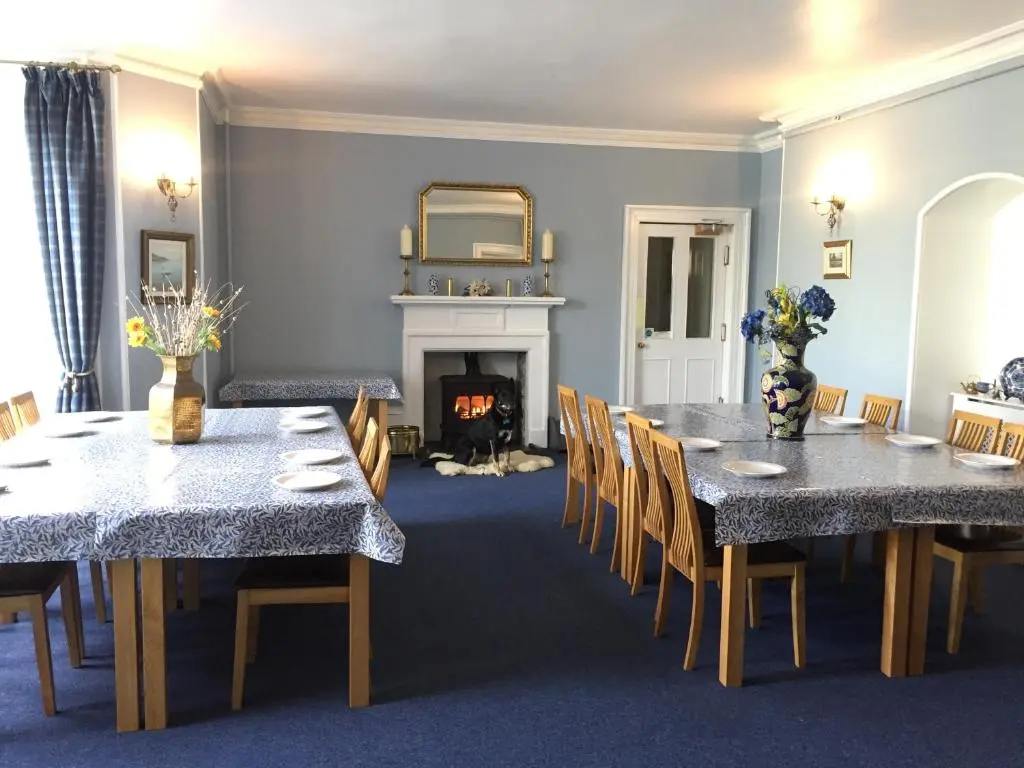 a dining room with two tables and a fireplace at Forse of Nature in Latheron