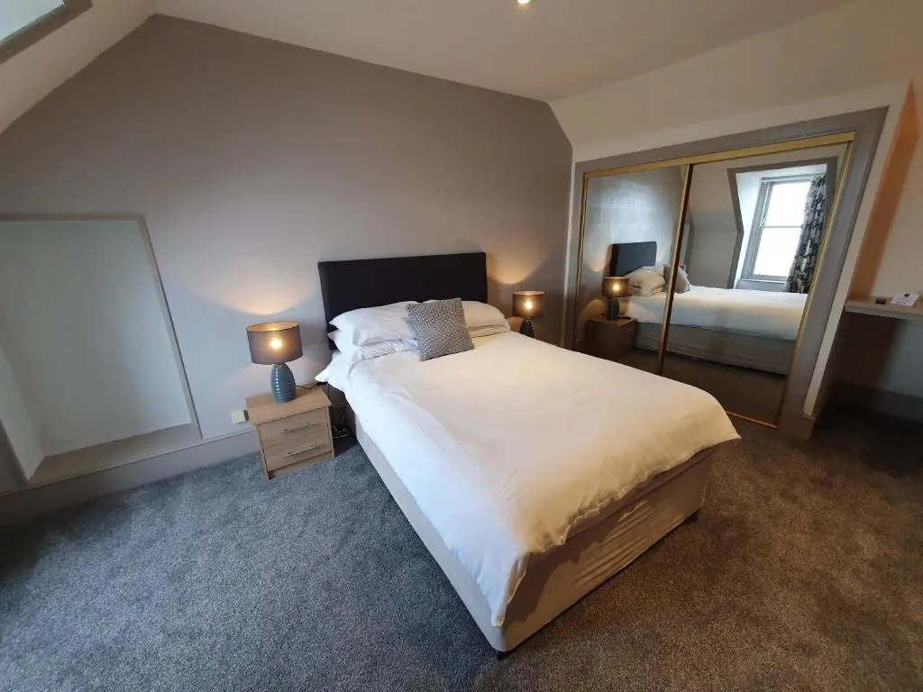 a bedroom with a large bed and a mirror at House by the Harbour - NC500 Route in Wick