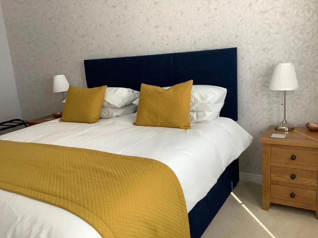 a bedroom with a large bed with yellow and white pillows at Hedgefield House Flat 34 in Inverness