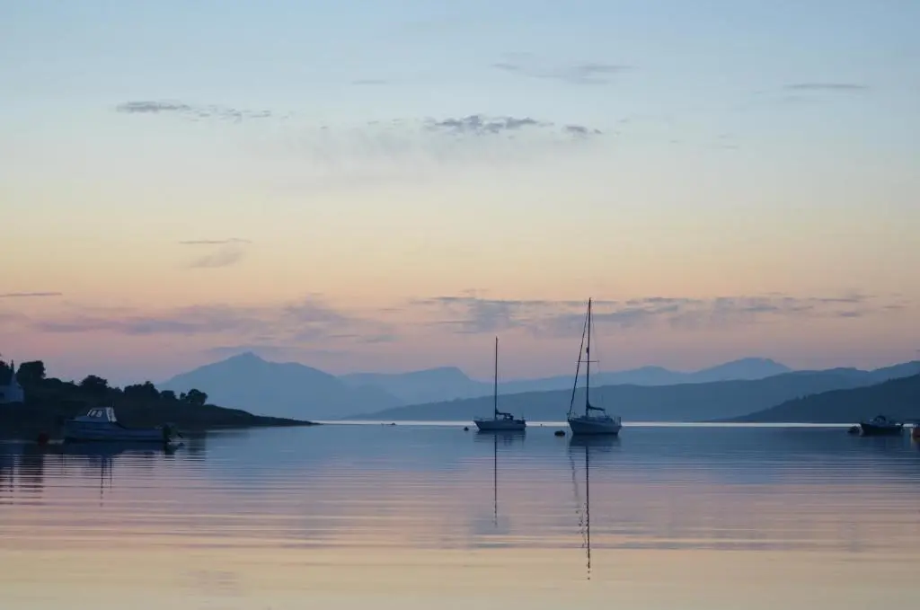 two boats sitting in the water at sunset at Holiday Inn Express Inverness by IHG in Inverness