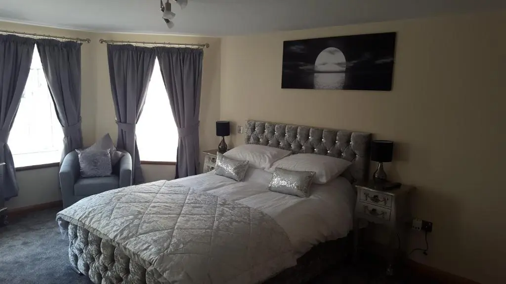 a bedroom with a large bed and two windows at Star Inn Rooms in Ardersier