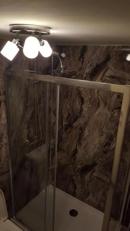 a bathroom with a shower with a stone wall at Star Inn Rooms in Ardersier