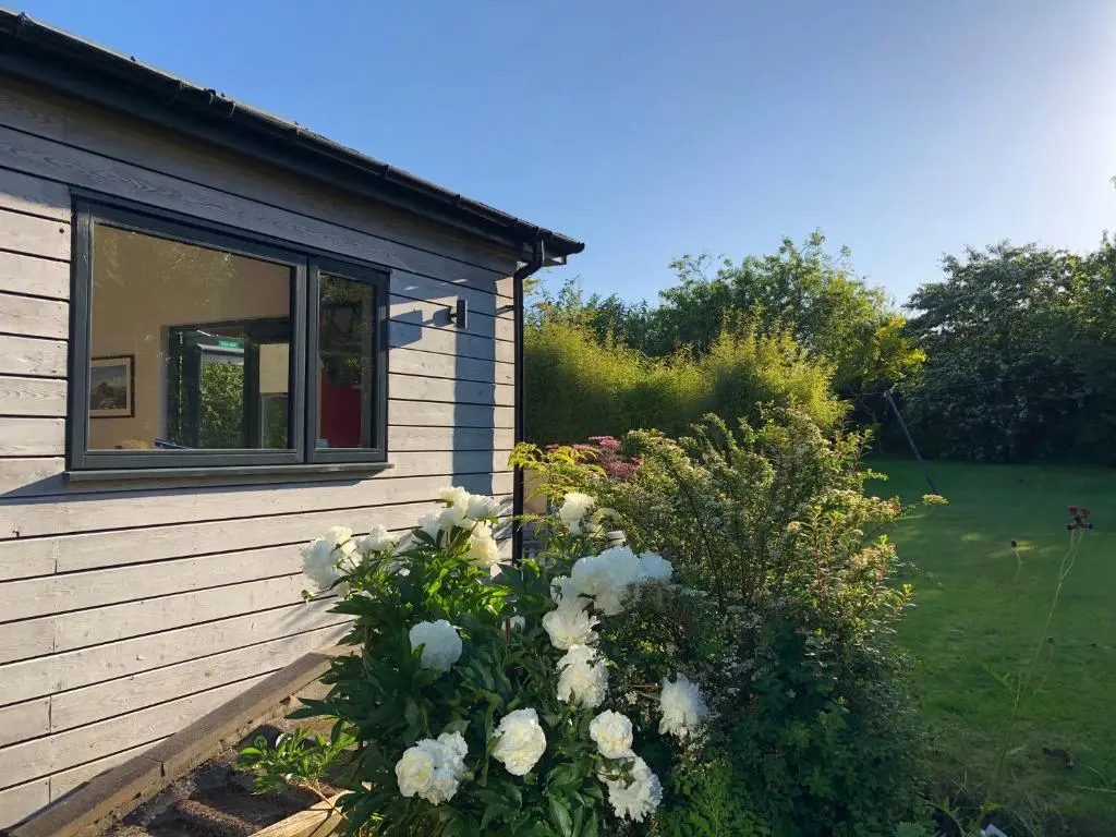 a bush of white flowers next to a house at The Wee Lodge in Inverness