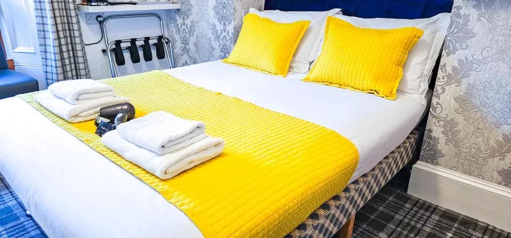 a bedroom with a bed with yellow sheets and towels at mySTAYINN Kinloch Lodge in Inverness
