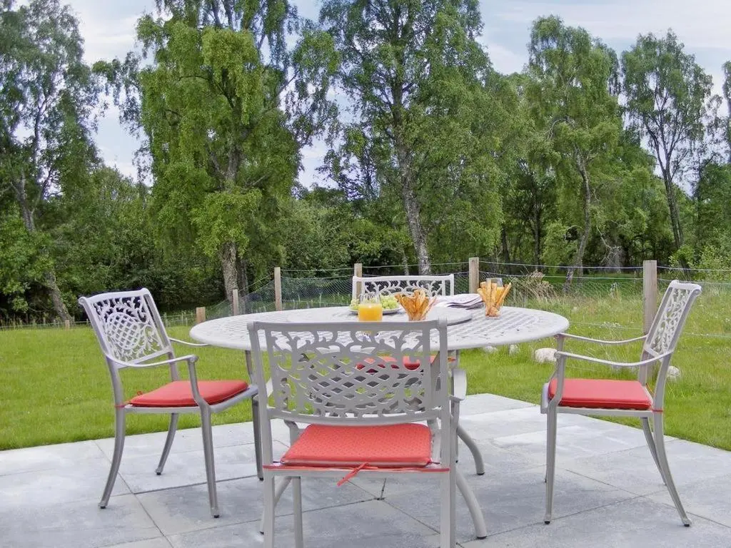 a patio table with three chairs and a table with drinks on it at Woodlands in Aviemore