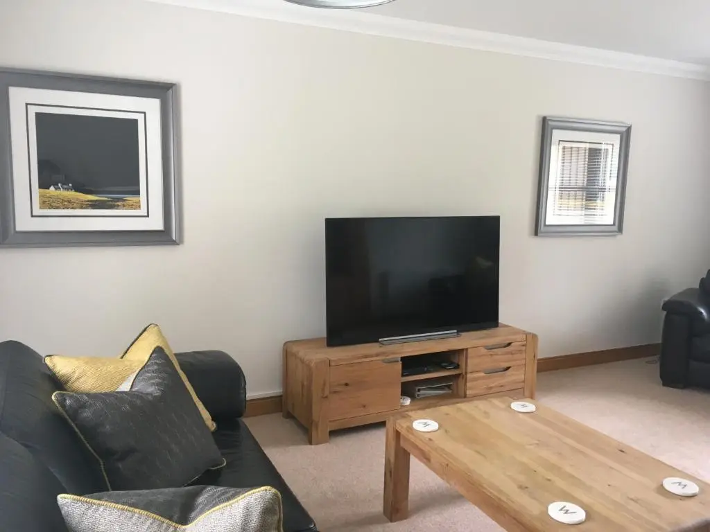 a living room with a flat screen tv and a wooden coffee table at Woodlands in Aviemore