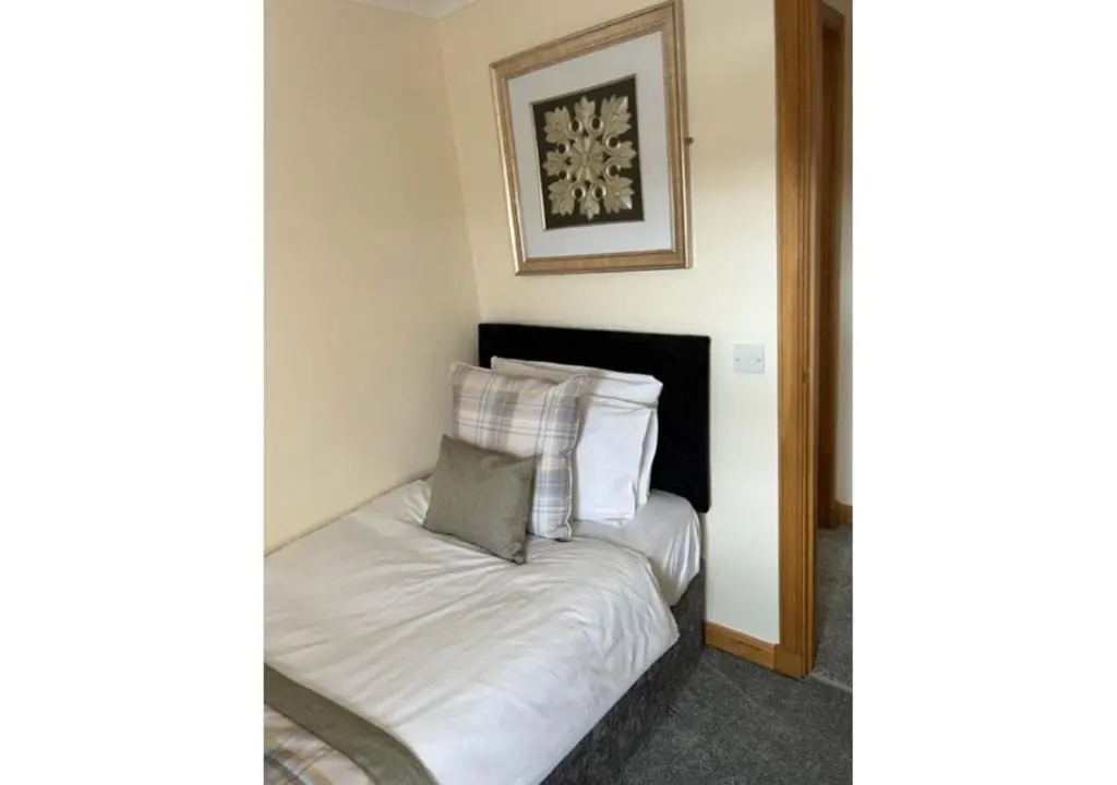 a bedroom with a bed with white sheets and pillows at The Waverley Inn Holiday Homes in Inverness