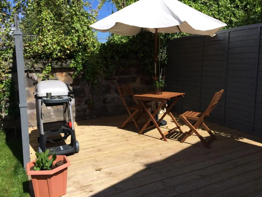a patio with an umbrella and a table and a grill at 32a railside in Inverness