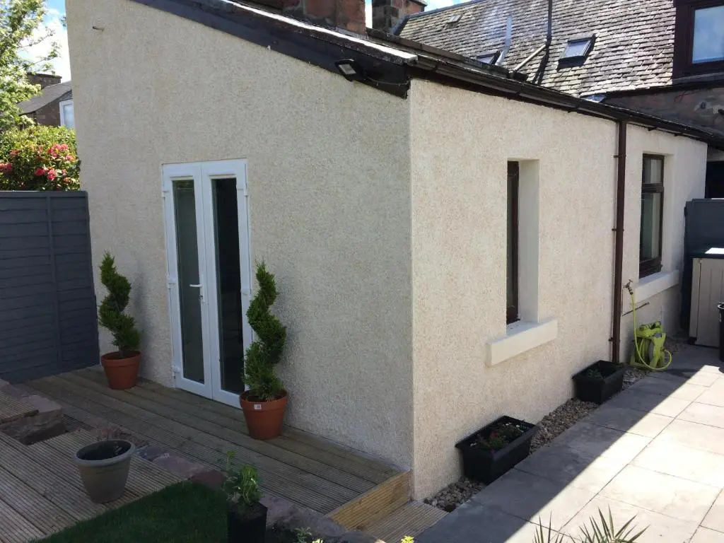 a house with potted plants on a wooden deck at 32a railside in Inverness