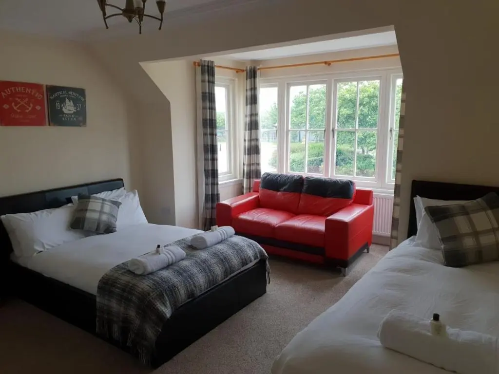 a living room with two beds and a red couch at The Ship Inn in Invergordon
