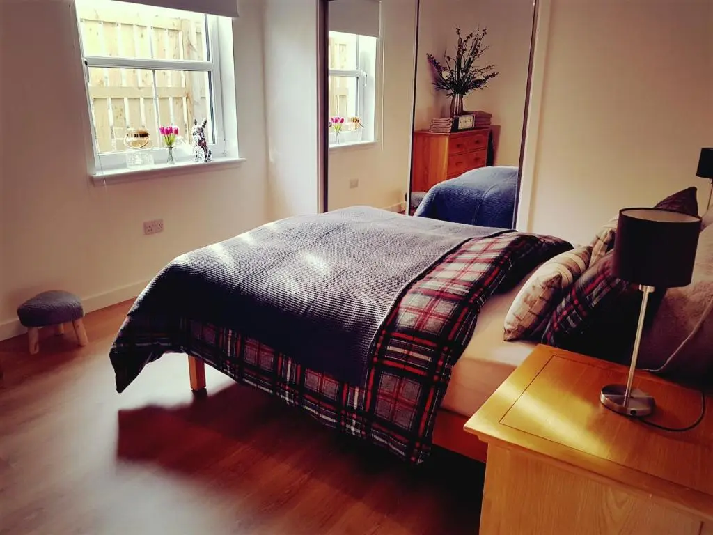 a bedroom with a bed and a table and a window at Yvi's 2Bedroom 2Bathroom Apartment in Inverurie