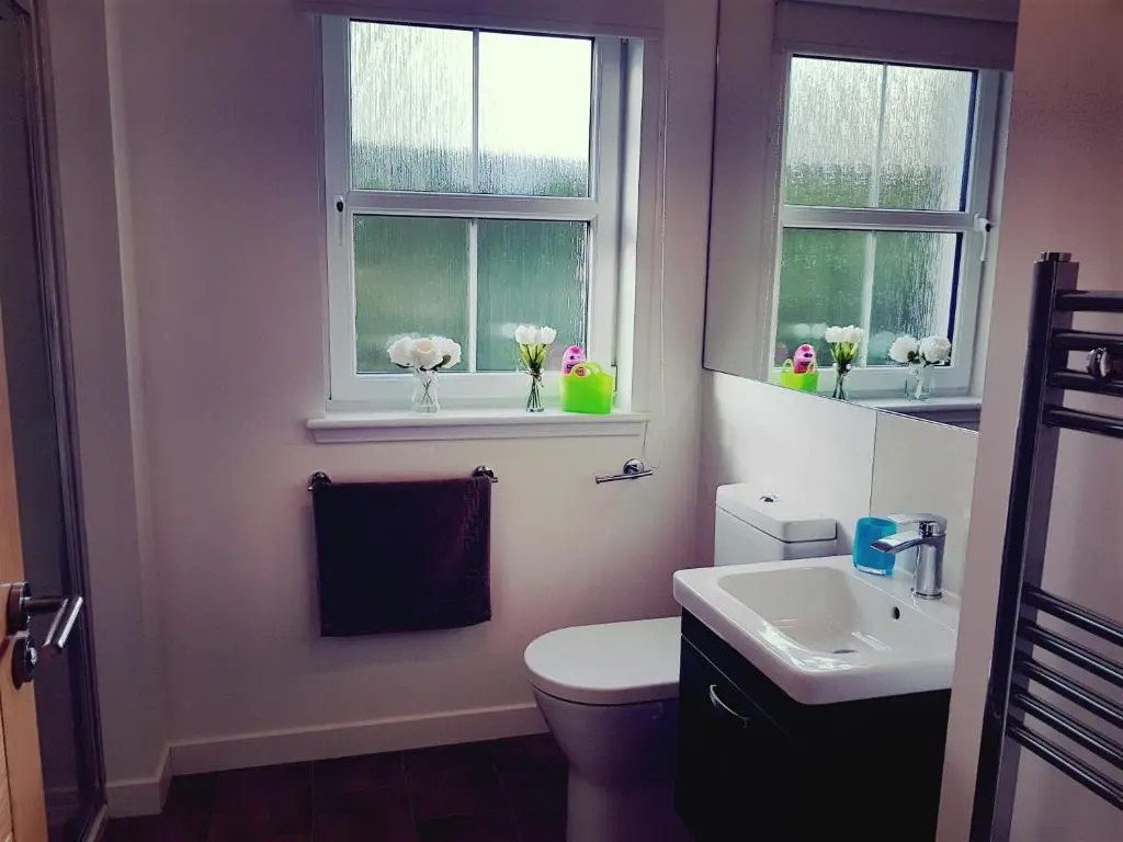 a bathroom with a toilet and a sink and two windows at Yvi's 2Bedroom 2Bathroom Apartment in Inverurie