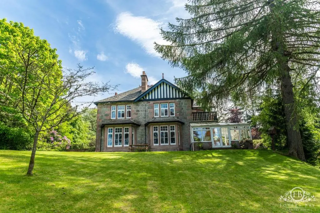 a large brick house with a tree in the yard at Foyers Bay Country House in Foyers