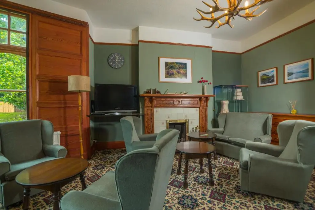 a living room with green walls and chairs and a fireplace at Foyers Bay Country House in Foyers