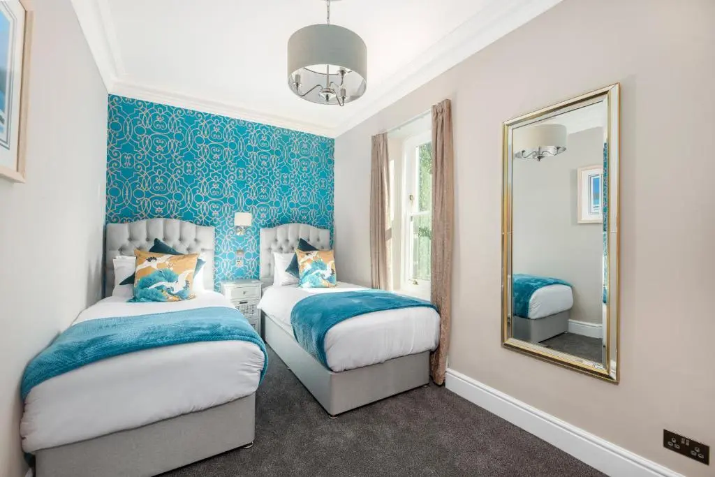 a bedroom with two beds and a mirror at Dryburgh Town House in Inverness