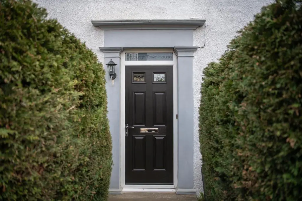 a black door in a white house with two bushes at Dryburgh Town House in Inverness