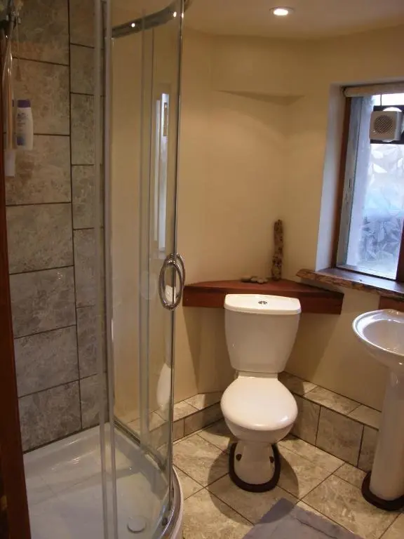 a bathroom with a toilet and a glass shower at Sunrise House in Inverfarigaig