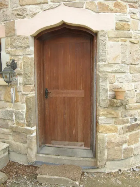 a wooden door in a stone building with a stone wall at Sunrise House in Inverfarigaig