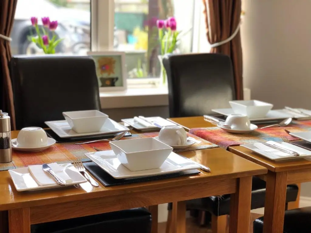 a wooden table with bowls and plates on it at Carisbrooke Guest House in Inverness