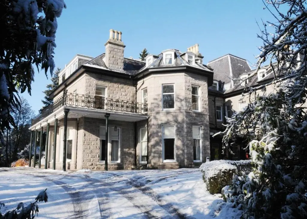 a large stone house with snow on the ground at Tor-Na-Coille Hotel in Banchory
