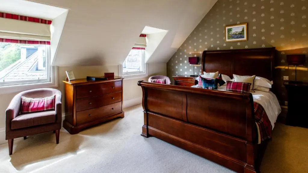 a bedroom with a bed and a dresser and a chair at Tor-Na-Coille Hotel in Banchory