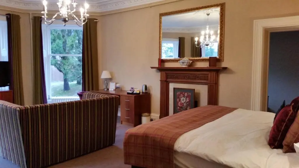 a bedroom with a bed and a mirror and a fireplace at Tor-Na-Coille Hotel in Banchory