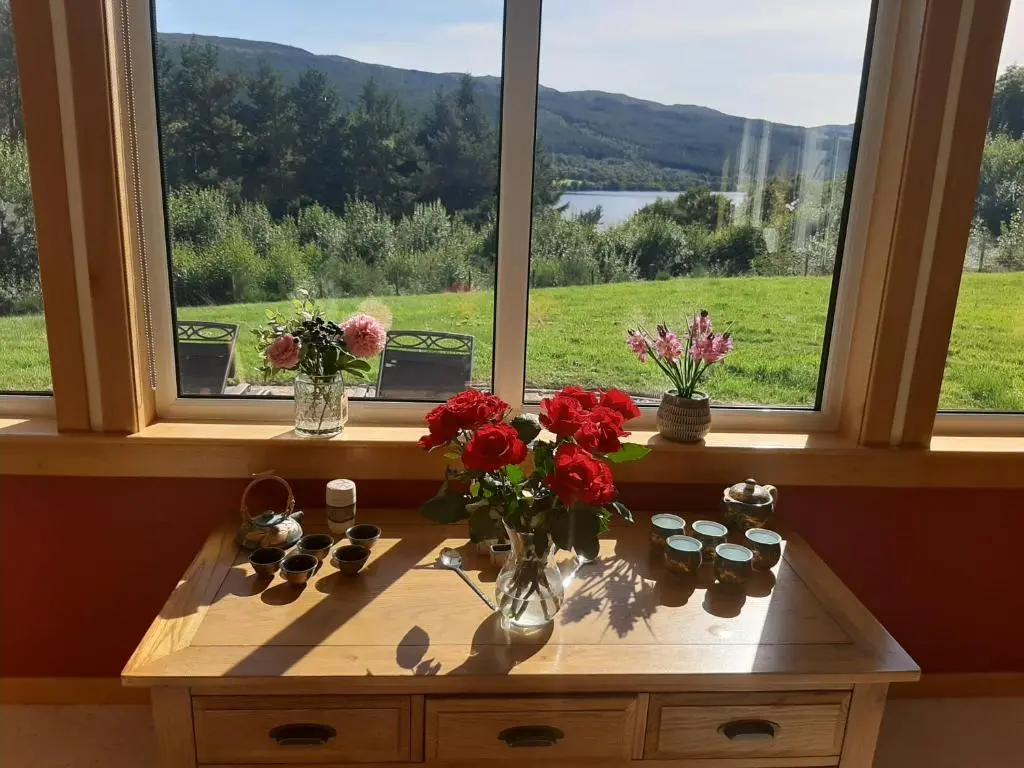 a table with flowers on it in front of a window at High March in Drumnadrochit