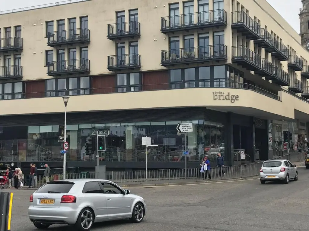 two cars are parked in front of a building at Apartment 306 By the Bridge in Inverness