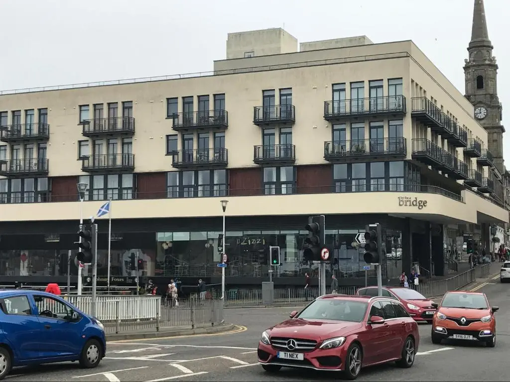 a busy city street with cars parked in front of a building at Apartment 306 By the Bridge in Inverness