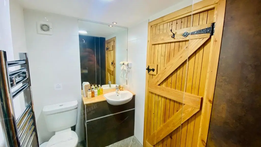 a bathroom with a wooden door and a toilet and a sink at Aultguish Inn in Garve