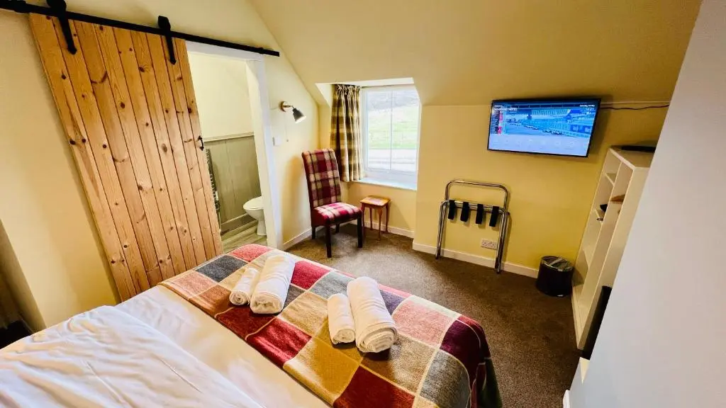 a bedroom with a bed with towels on it at Aultguish Inn in Garve