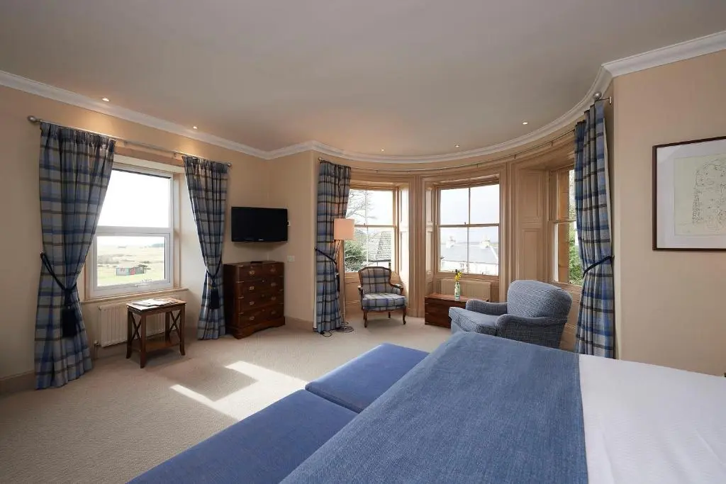 a bedroom with a blue bed and a living room at Royal Golf Hotel, by Highland Coast Hotels in Dornoch