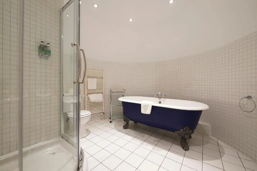 a bathroom with a blue tub and a toilet at Royal Golf Hotel, by Highland Coast Hotels in Dornoch