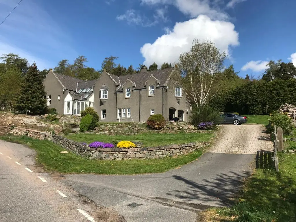 a house on a road with flowers in the driveway at Whitehill in Finzean