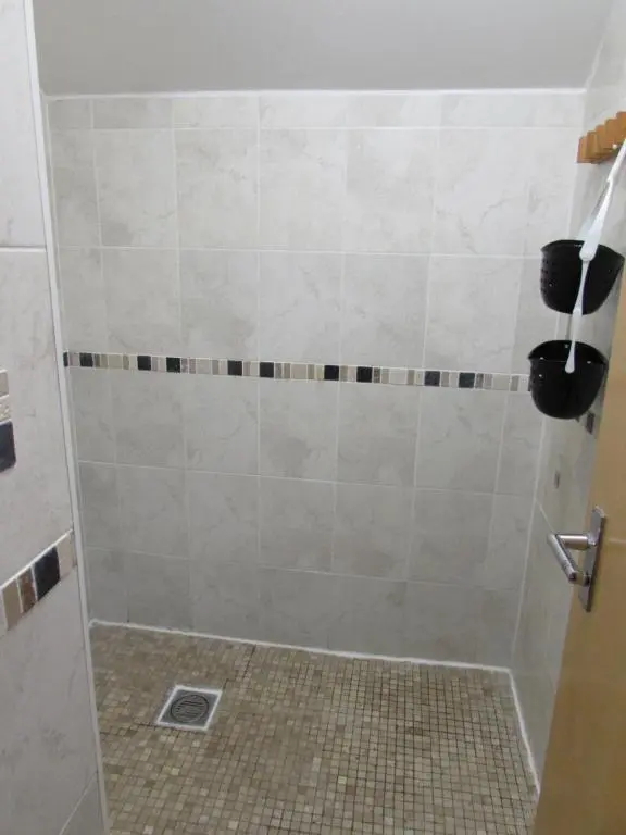 a shower in a bathroom with a tiled floor at Ballater Hostel in Ballater