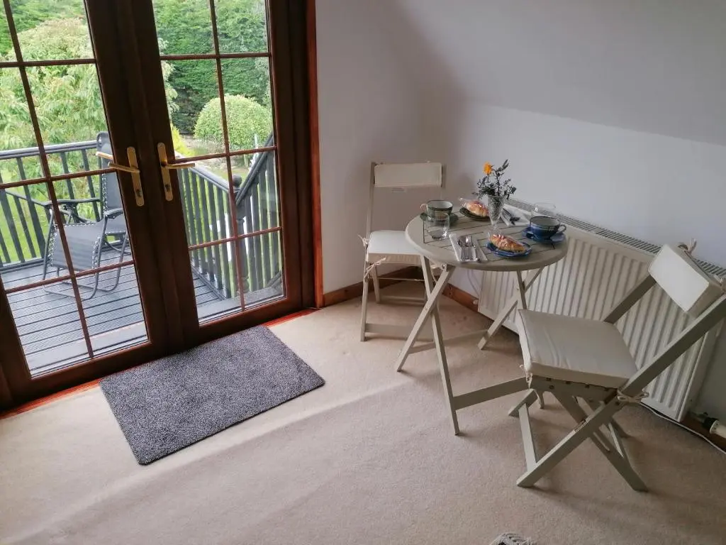 a table and chairs in a room with a balcony at Canterra Cottage in Tain