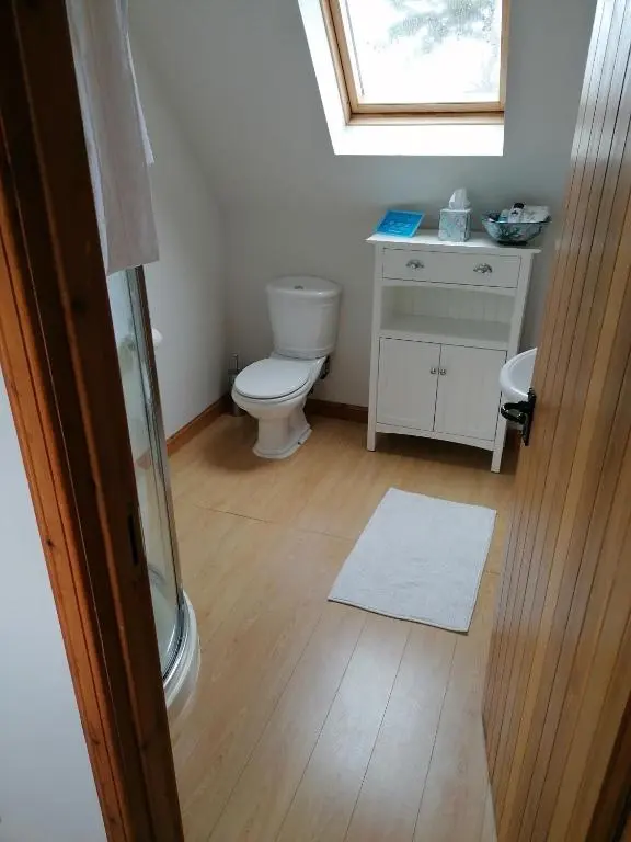 a bathroom with a toilet and a sink and a window at Canterra Cottage in Tain