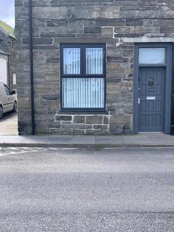 a stone building with a blue door and a window at Harbour quay in Wick