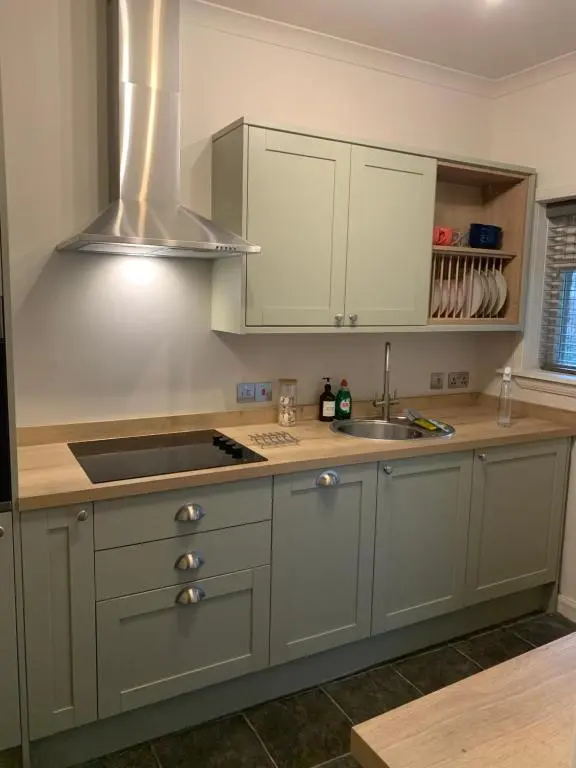 a kitchen with white cabinets and a sink at Harbour quay in Wick