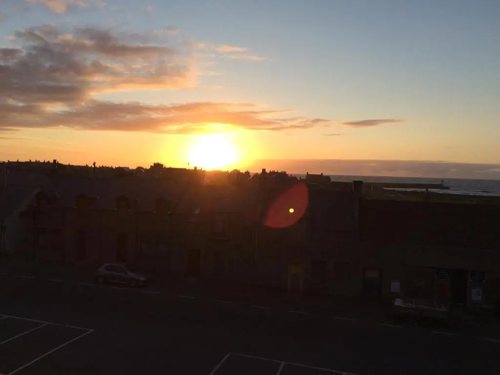 a sunset with the sun setting behind some buildings at The Davron Hotel in Fraserburgh