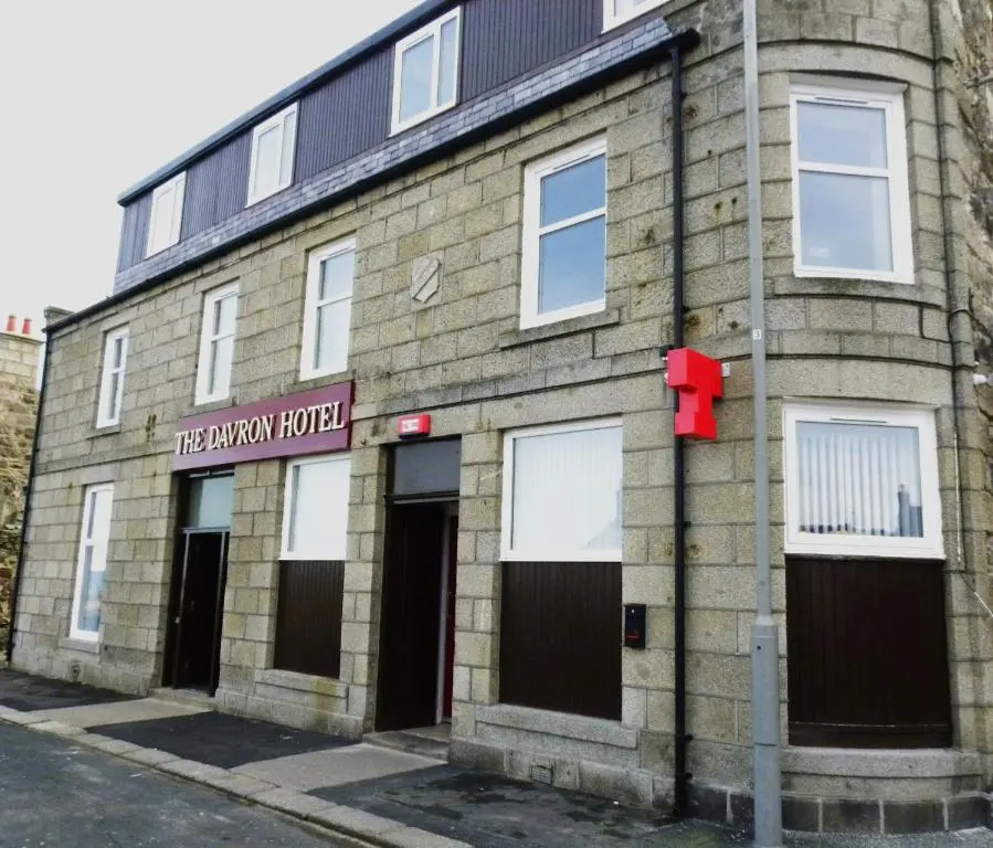 an old brick building with a red sign on it at The Davron Hotel in Fraserburgh