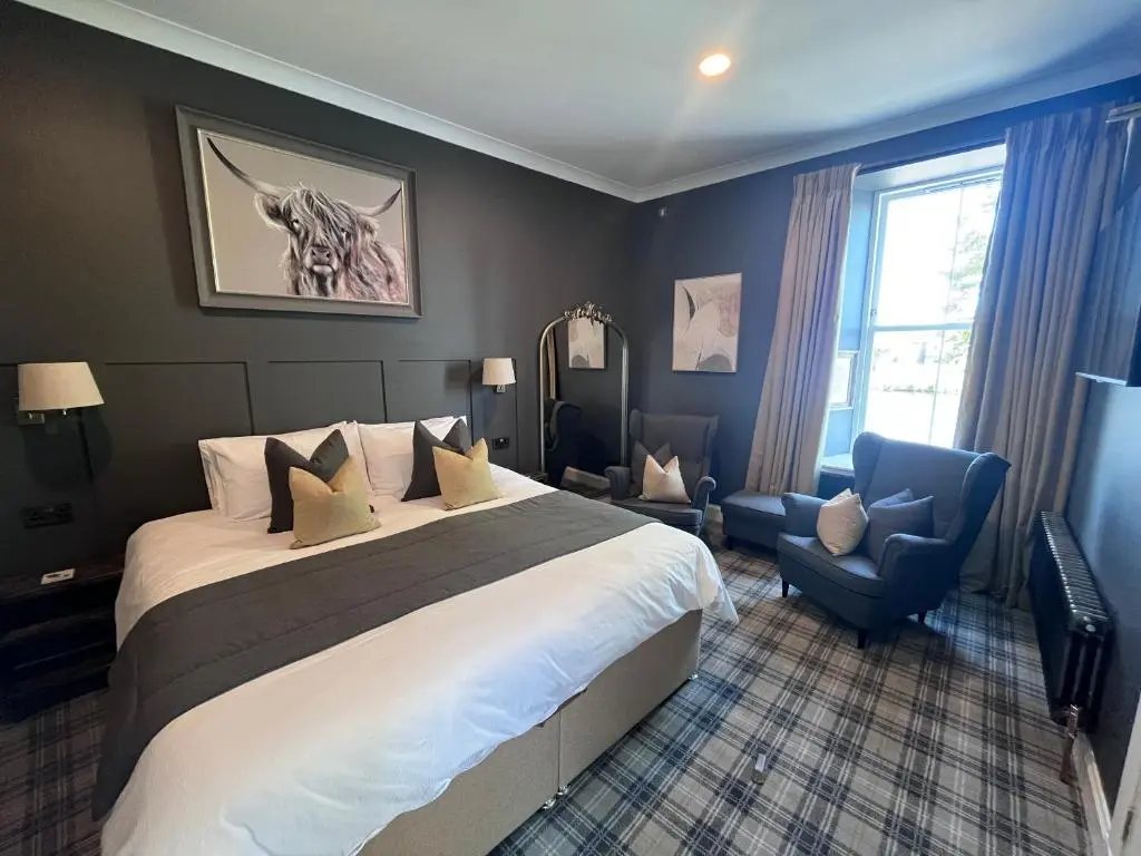 a hotel room with a large bed and a chair at Fraser House in Inverness